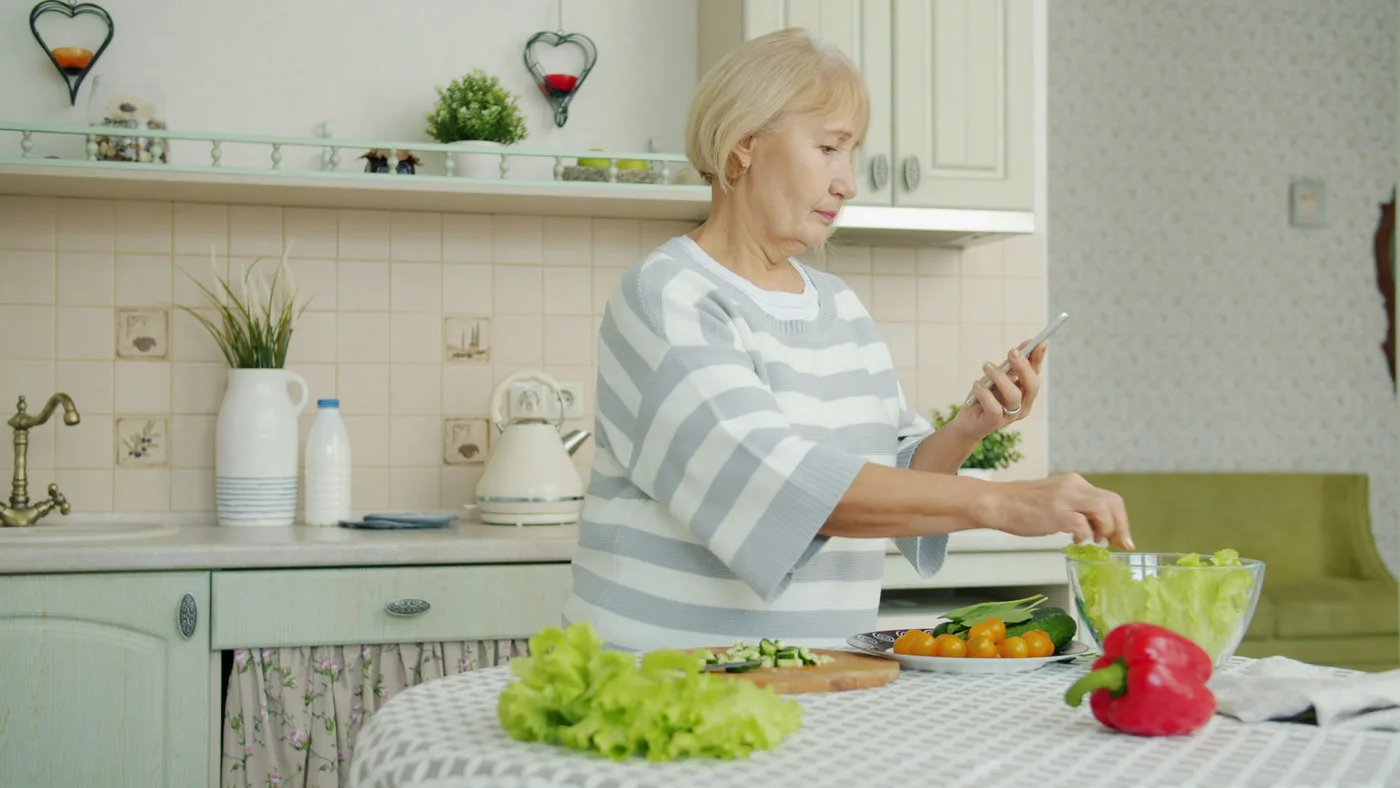 Aînée préparant un repas dans sa cuisine, soutien à domicile et répit proche aidant